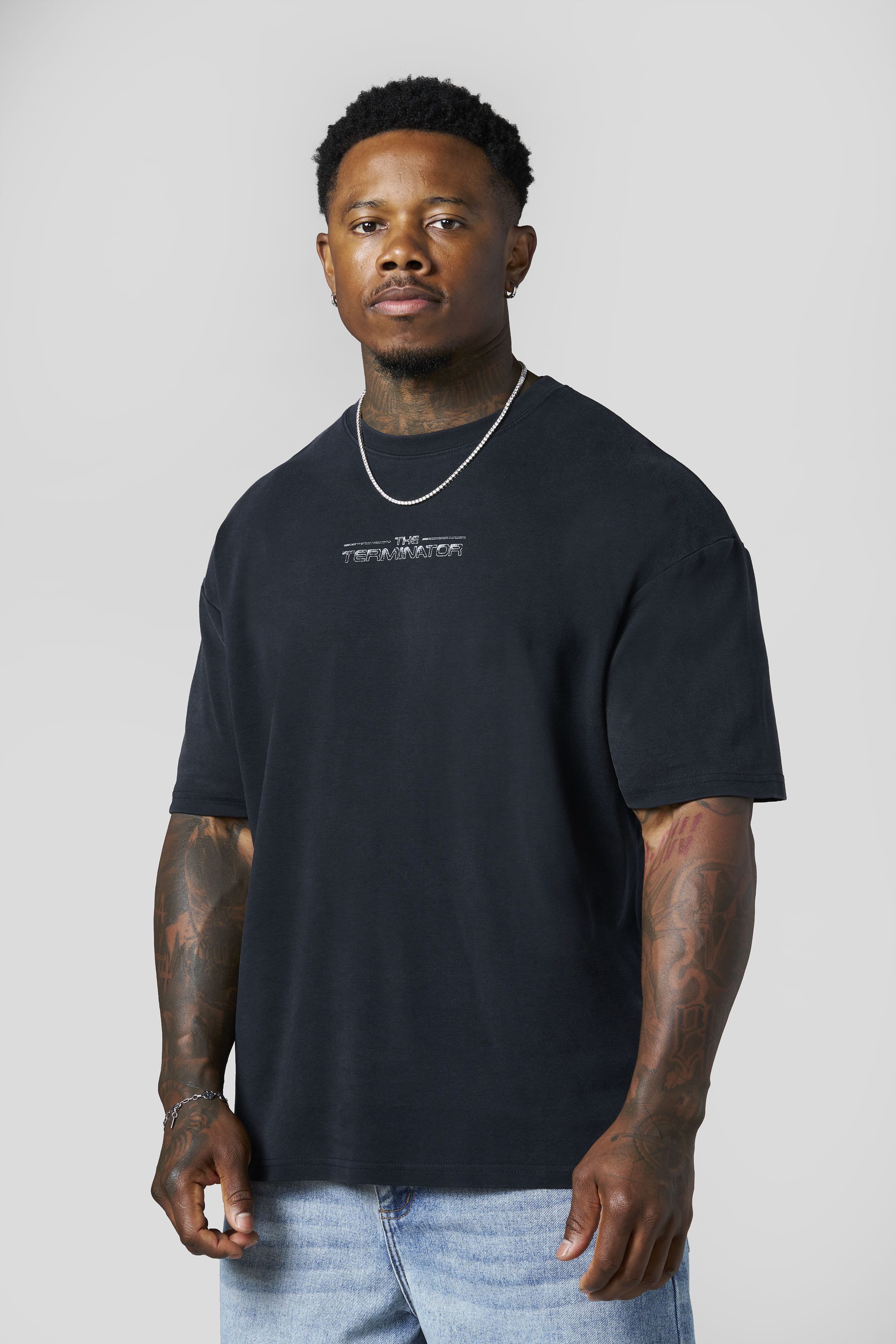 Man wearing a black t-shirt with a logo on a plain background
